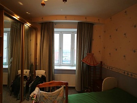 ораньжевый торшер у окна спальни с темными шторами в современной трешке