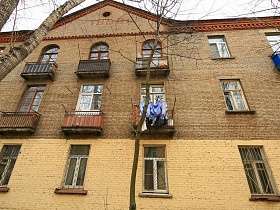 вид на кирпичный трехэтажный дом с узкими окнами советских времен
