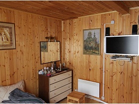 картины и белый телевизор в гостиной с деревянными стенами и потолком дачи СССР