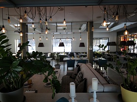 вид на уютный просторный светлый зал стильного ресторана сквозь открытый стеллаж