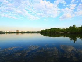прекрасный вид водной глади синего озера с отражением белых перистых облаков и неба