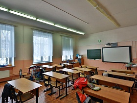 обычный школьный класс с партами, учительсим столом и досками на стене
