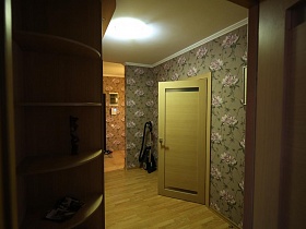 открытые боковые полки шкафа, пылесос в углу длинного коридора современной трехкомнатной актерской квартиры