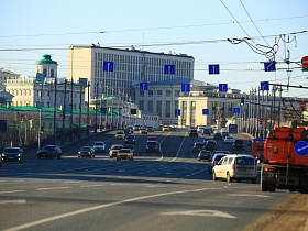 оживленное движение на широком каменном мосту с металлическим ограждением, фонарными столбами вдоль дороги у Кремля