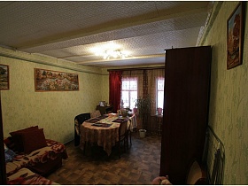 гостиная с угловым диваном, большим овальным столом, шкафом и множество картин на стенах