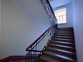 бетонные ступени лестницы с перилами между этажами светлого подъезда с большим окном на лестничной площадке жилого дома на Новослободской