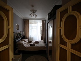 открытые филенчатые двери в просторную спальню с серыми стенами
