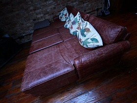 бордовый кожанный диван в разложенном виде с подушками