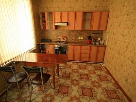 коричневая кухня у стены с цветными обоями на полу с коричневой плиткой в комнате двухэтажного пустого дома под съем