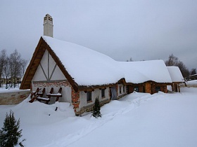 домики с остроконечной крышей и печной трубой на территории ресторана , стилизованного под хутор в коттеджном поселке