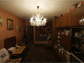 посуда, фотографии, сувениры, телевизор и прочее на полках коричневой мебельной стенки в зале с большим ковром на полу квартиры СССР 80-89 стиля