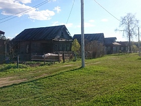 бетонные столбы с линией электропередач вдоль улицы с рядом старых деревянных домов под треугольной крышей