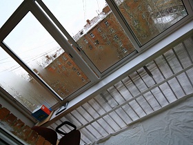 черное компьютерное кресло на полу балкона с остеклением двухкомнатной современной квартиры художника
