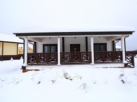 фасад красивого современного съемного коттеджа с открытой верандой под крышей в зимнее время