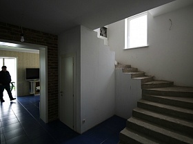 широкая полукруглая лестница у белой стены небольшой комнаты дома с частичным недостроем