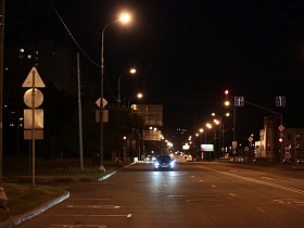 синие дорожные указатели на проводах, многочисленные дорожные знаки по обочине широкой улице Крылатские Холмы с разметкой скорости на дорожном полотне