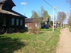 бревенчатый деревянный дом на два хозяина вдоль проселочной дороги на одной из улиц старой деревни