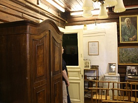 старинный деревянный шкаф, деревянные стулья со спинкой у открытой двери в комнате с белой люстрой художественной дачи-музей