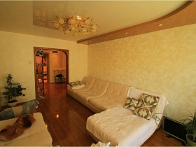 угловой светлый диван с подушками и комнатными цветами в гостиной простой двушки в Долгопрудном
