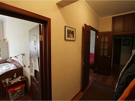 желтые стены прихожей с открытыми деревянными дверьми в разные комнаты квартиры педагога