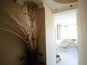 композиция из сухих веток в вазе на полке у дверного проема в кухню современной трешки многоэтажного дома