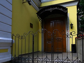 металлические рельефные ворота крыльца под резной крышей красивого особняка в Москве