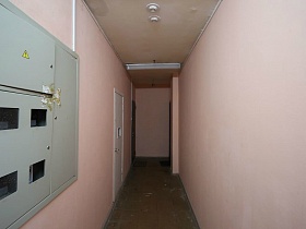 электросчетчики на стене розового коридора с квартирами на этаже многоэтажного жилого дома