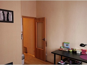 картины на светлой стене и на полу кухни с коричневым прямоугольным обеденным столом простой квартиры с большой мансардой