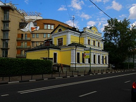 красивый компактный желтый двухэтажный особняк с высоким цоколем среди зелени в Москве