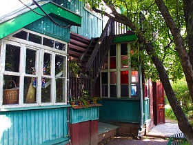 деревянная лестница с перилами на второй этаж художественной дачи-музей над верандой с цветными стеклами на окнах