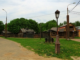 деревянный колодец под крышей на зеленой полянке с уличными фонарями на окраине старого городка для съемок кино