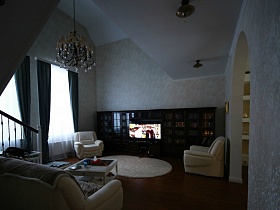 общий вид гостиной с белым ковром у кресел, люстрой на светлом потолке добротного современного кирпичного дома