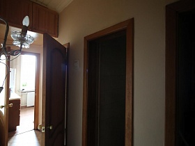бра с лампочкой- свечой на стене коридора с открытыми дверьми в отдельные комнаты сталинской квартиры