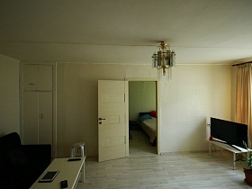 встроенный белый шкаф у мягкого дивана с журнальным столиком в гостиной съемной квартиры