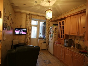 кухня  с бежевой плиткой на полу, белым холодильником в углу комнаты и цилиндрическим светильником на потолке в современной трешке