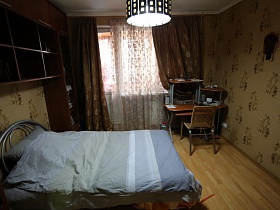компьтерный стол с полочками и плетенный стул у окна спальни актерской трекхкомнатной квартиры