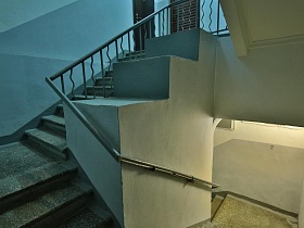 бетонные ступени под мрамор на лестничных пролетах винтовой лестницы в чистом стильном сером подъезде после ремонта жилого многоэтажного дома