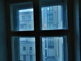 вид из окна на лестничной площадке серого стильного подъезда 12 жилого многоэтажного дома Советского времени