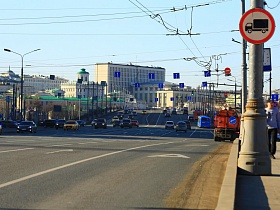 городской и общественный транспорт на оживленной дороге с размеченными полосами и дорожными знаками на проводах над большим каменным мостом у Кремля