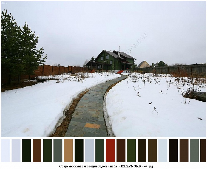 расчищенная от снега дорожка с тротуарной плиткой на большом участке с высокими елями и уютным современным зеленым домом-избой для съемок кино