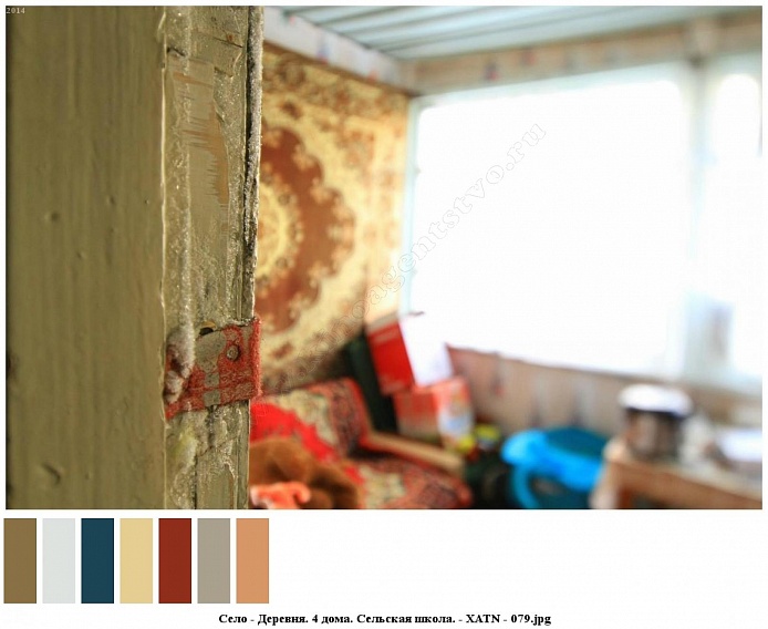 ковер на стене и диване, стол с посудой, картонные коробки у окна веранды сельского деревянного дома