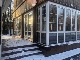 снег на ступенях крыльца у входных дверей в помещение уютного современного кафе-стекляшки