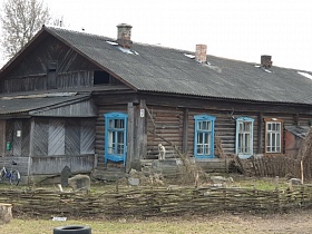 старый бревенчатый барачный дом на несколько хозяев с плетенным забором, крытой верандой, окрашенными наличниками на окнах в Акуловке для съемок кино