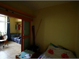 красные маки на белом постельном большой кровати в небольшой спаьной комнате с желтыми стенами двухкомнатной квартиры с видом на Москва-сити