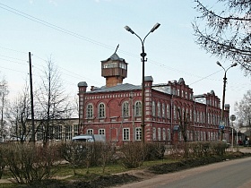 старинная кирпичная двухэтажная школа с красивым фасадом и арочными окнами вдоль дороги