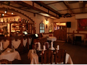 коричнево-кремовое двухцетное оформление уютного зала с деревянными двухстворчатыми входными дверьми ресторана с кавказким интерьером