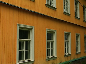 желтый деревянный двухэтажный дощатый дом с белыми наличниками в старом городке