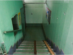 бетонные ступени с пандусом на лестничной клетке с зелеными стенами в подъезде панельного дома