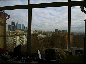 соседние жилые многоэтажные дома из окна застекленного балкона с захламленным подоконником двухкомнатной квартиры с видом на Москва-сити