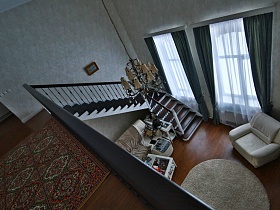 общий вид темной лестницы с перилами и выходом в светлую гостинную современного кирпичного дома